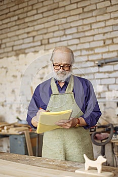 Nice pensioner is drawing a graph in the home workshop