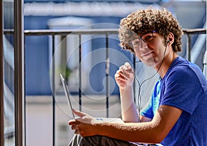 Nice photo of a young Caucasian man working with his laptop and earphones.