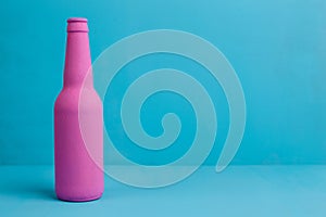 Nice pink beer bottle on blue background. Deceptive attraction o