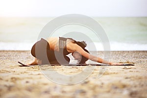 Nice portrait of young woman doing yoga or meditating on the seaside.