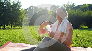 Nice positive sporty woman resting after sport in the park