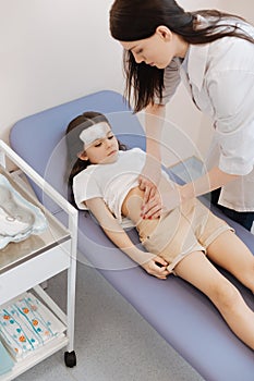 Nice professional therapeutist examining the girls stomach