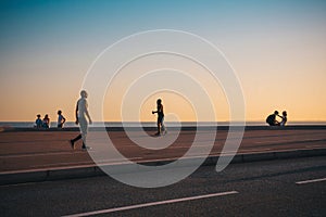 Nice, Provence / France - September 28, 2018: Silhouettes of passersby against the sunset over the sea