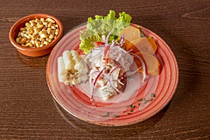 Nice red plate with Peruvian-style fish ceviche with white corn, cancha and sweet potato slices photo
