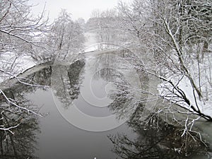 Nice river with smooth water surface and trees in frost