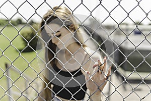 Nice and sad teen girl standing portrait through fence