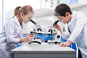 Nice smart children looking into microscopes