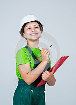 Nice smile. Repair planning. kid in hard hat making notes. child hold document folder. Kid learn how to be a