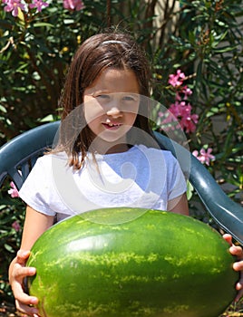 Nice smiling little girl with an enormous WATERMELON