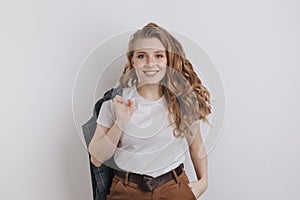 Nice smiling woman in a white t-shurt holding her jacket posing isolated over the white background