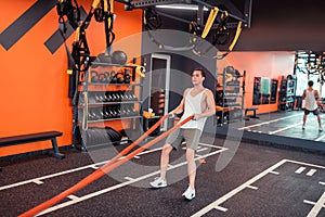 Nice sportive young man holding orange ropes