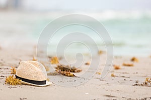 Nice straw hat laying on the sand. Beautiful ocean beach background. Outdoors. Vacation time. End of summer vacations