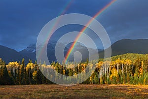 Nice summer rainbow over the mountains. Amazing rainy and cloudy day. Canadian Rocky Mountains, Canada.