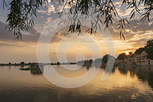 Nice sunset at Gadisar lake, Jaisalmer, Rajasthan, India. Setting sun and colorful clouds in the sky with view of the Gadisar lake