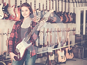 Nice teen girl examining various electric guitars