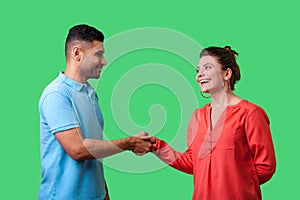 Nice to meet you! Portrait of happy young couple in casual wear shaking hands. isolated on green background