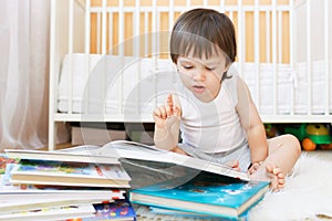 Nice toddler reading books against white bed