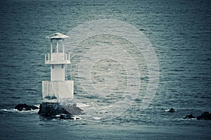 Nice view of the lighthouse in the sea, vintage photo style.