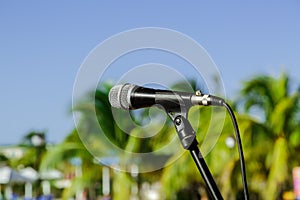 Nice view of microphone on stand in outdoor tropical garden against blue sky background
