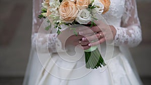 Nice wedding bouquet in bride`s hand. Clip. Fiancee in a beautiful white dress holding a beautiful bouquet of wedding