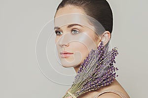 Nice woman with clear skin and lavender flowers close up portrait