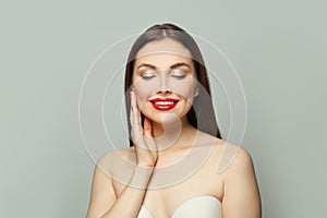 Nice woman with clear skin smiling on white background. Eyes closed. Skincare and facial treatment concept