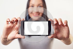 A nice woman holding a smartphone with an empty white screen with two hands horizontally and smiling On white background