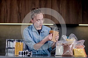 Nice woman organizes the placement of food in plastic cans. Woman signs cans of bulk food