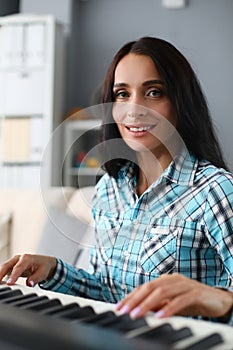 Nice woman playing melody synthesizer at home