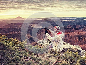 Nice woman in warm clothes photographing daybreak over  land