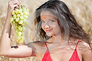 Nice woman in wheat field eating grapes.