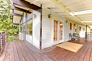Nice wooden porch with brown trim, white glass doors and metal c