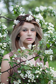 Nice young adult woman female model with clean fresh skin, make-up and brown hair in blossom garden on green leaves background