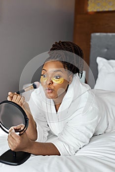 Beautiful young African woman with gold eye mask, medical eye antiwrinkle patches and doing natural nude make-up photo