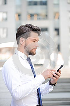 Nice young businessman holding mobile phone