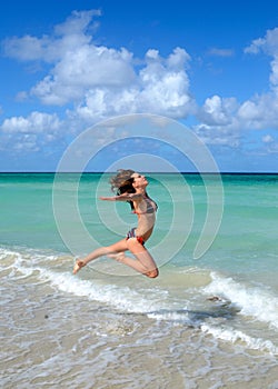 Nice young girl is jumping close to ocean