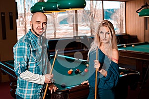 Nice young lovely couple plays billiard and smiling on camera