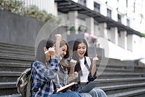Nice young students use laptop after class sitting outdoors. girls wear casual clothes in spring. Concept of modern