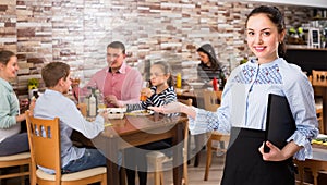 nice young waitress warmly welcoming guests to family cafe