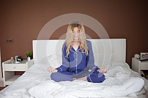 Nice young woman, cheerful morning, stretches, sitting on the bed.