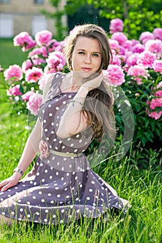 Nice young woman in the park near peonies