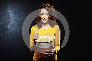 Nice young woman playing on camera with popcorn looking straight