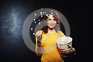 Nice young woman throwing popcorn up in the air smiling