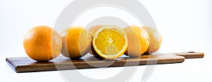 Nicely colored oranges on a white background - front and back lined next to each other on a wooden board