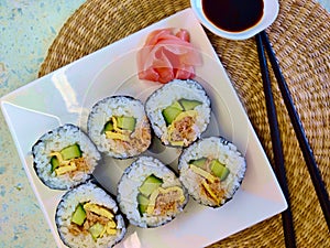 Nicely decorated plate with six pieces of sushi with cucumber, tuna, and egg in it