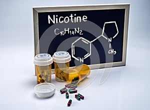 Nicotine written by hand on a whiteboard next to bottles of capsules