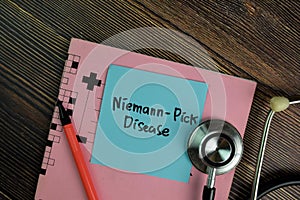 Niemann-Pick Disease write on sticky notes isolated on Wooden Table photo