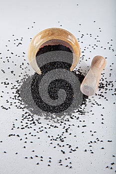 Nigella sativa seeds also known as black cumin, kalo jeera, kalonji and black caraway in iron scoop and mortar on white wooden