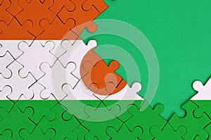 Niger flag is depicted on a completed jigsaw puzzle with free green copy space on the right side