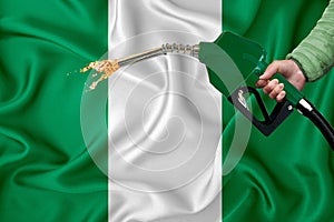NIGERIA flag Close-up shot on waving background texture with Fuel pump nozzle in hand. The concept of design solutions. 3d